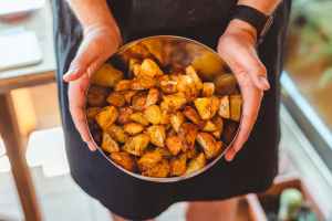 cook showing bowl with appetizing fried potatoes