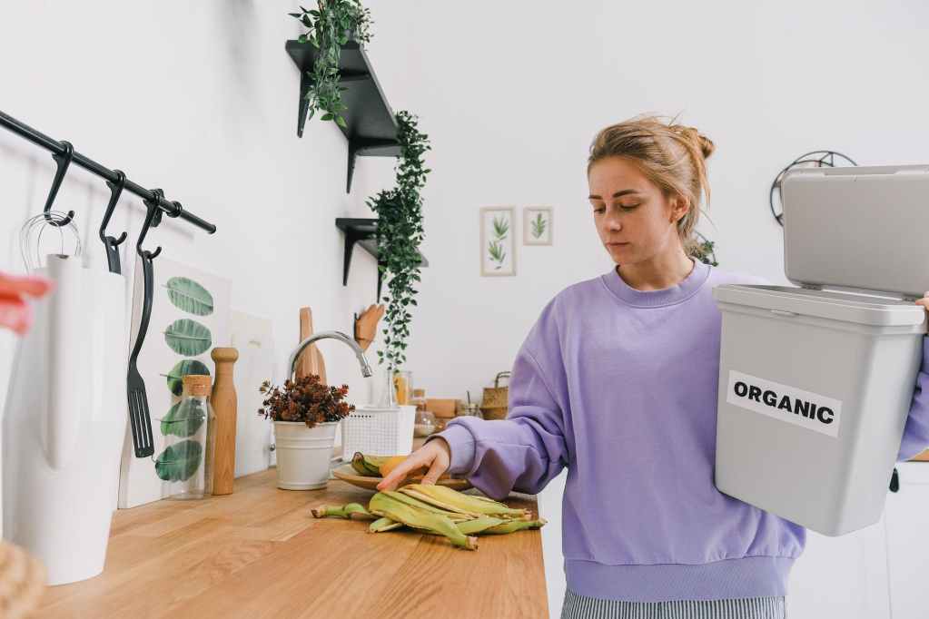 calm female sorting organic trash in kitchen in light room