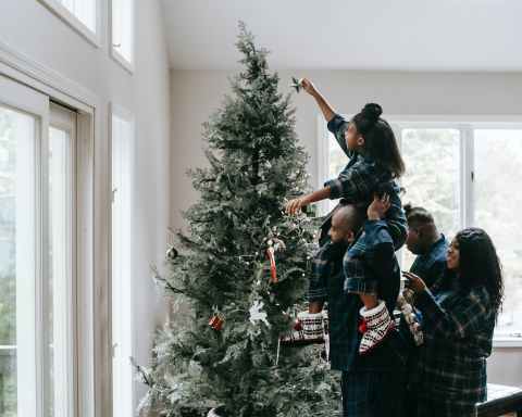 a girl putting a christmas star on a christmas tree