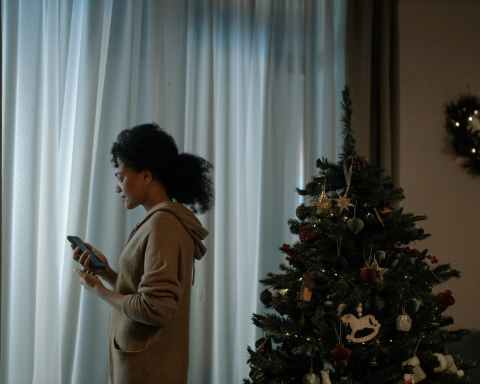 woman with a cellphone standing beside a christmas tree
